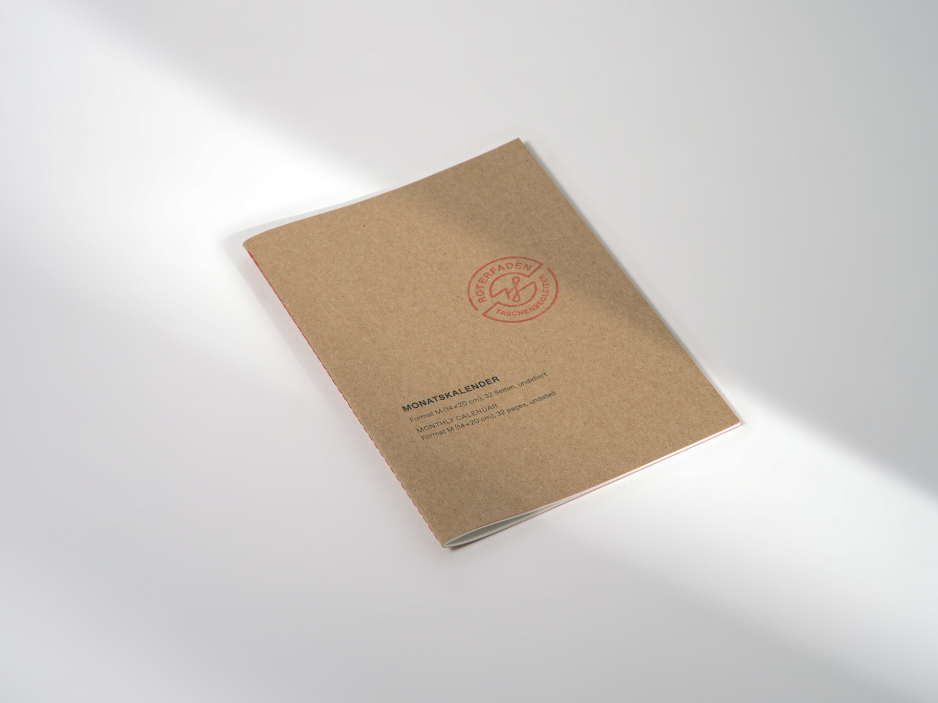 Undatierter Monatskalender im Format M (14 × 20 cm) für A5 mit rotem Faden genäht und festem Einband aus Recyclingkarton. 32 Seiten mit farbigem Vorsatzpapier